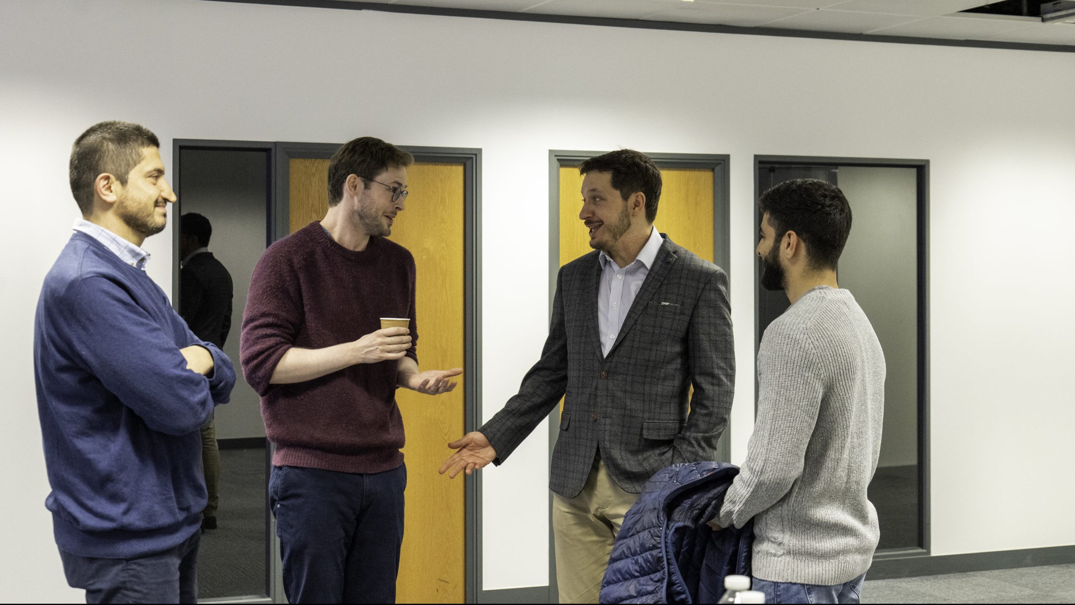 Three colleagues talking in a corridor at WF House between sessions.