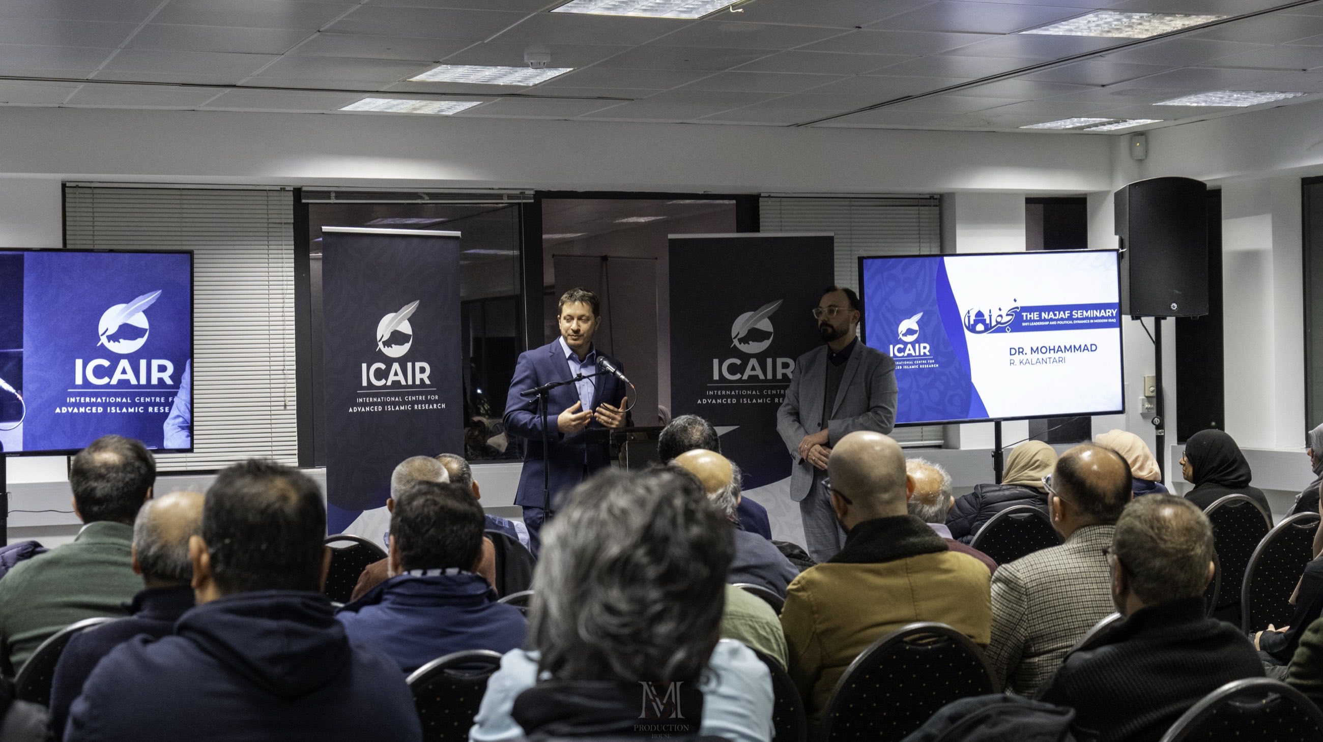 Alexander Khaleeli speaking at an ICAIR seminar on the Najaf seminary, with Dr Mohammad R. Kalantari beside him and a full audience at WF House.