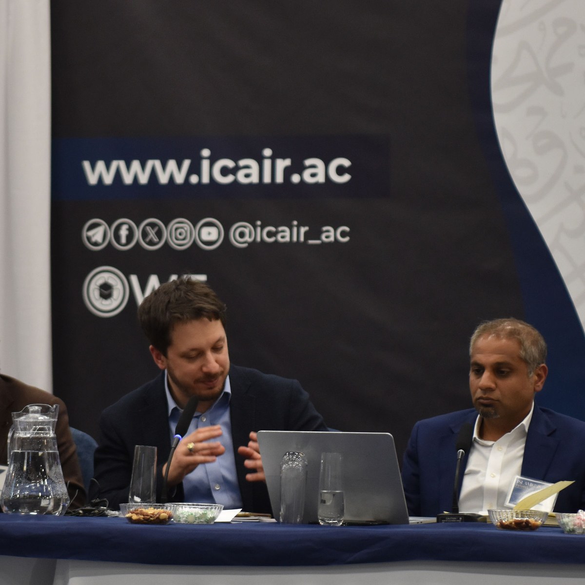 Panellists seated at a table beneath an ICAIR backdrop.