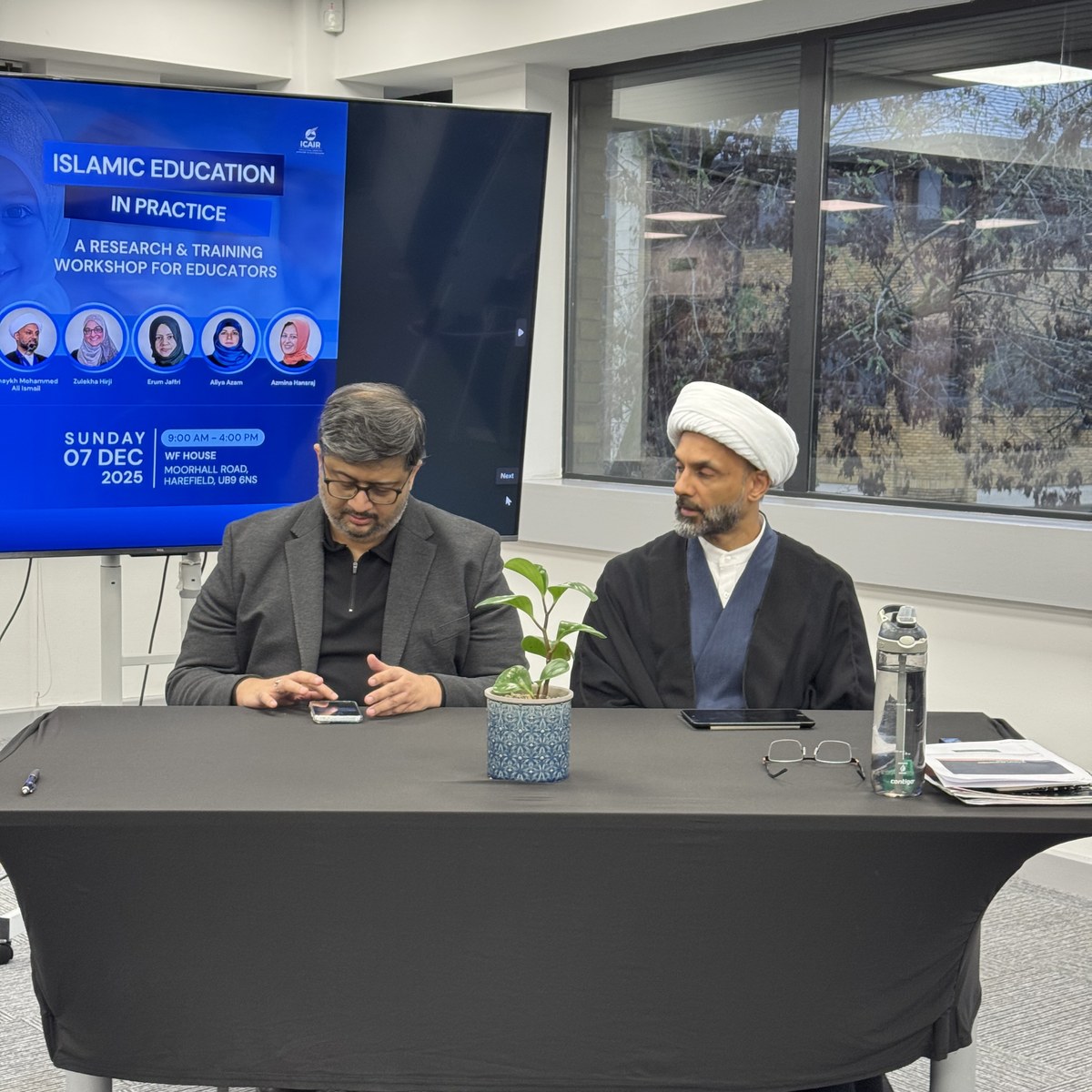 Two speakers seated at the front of the workshop, beside a screen announcing Islamic Education in Practice, a research and training workshop for educators held at WF House on 7 December 2025.